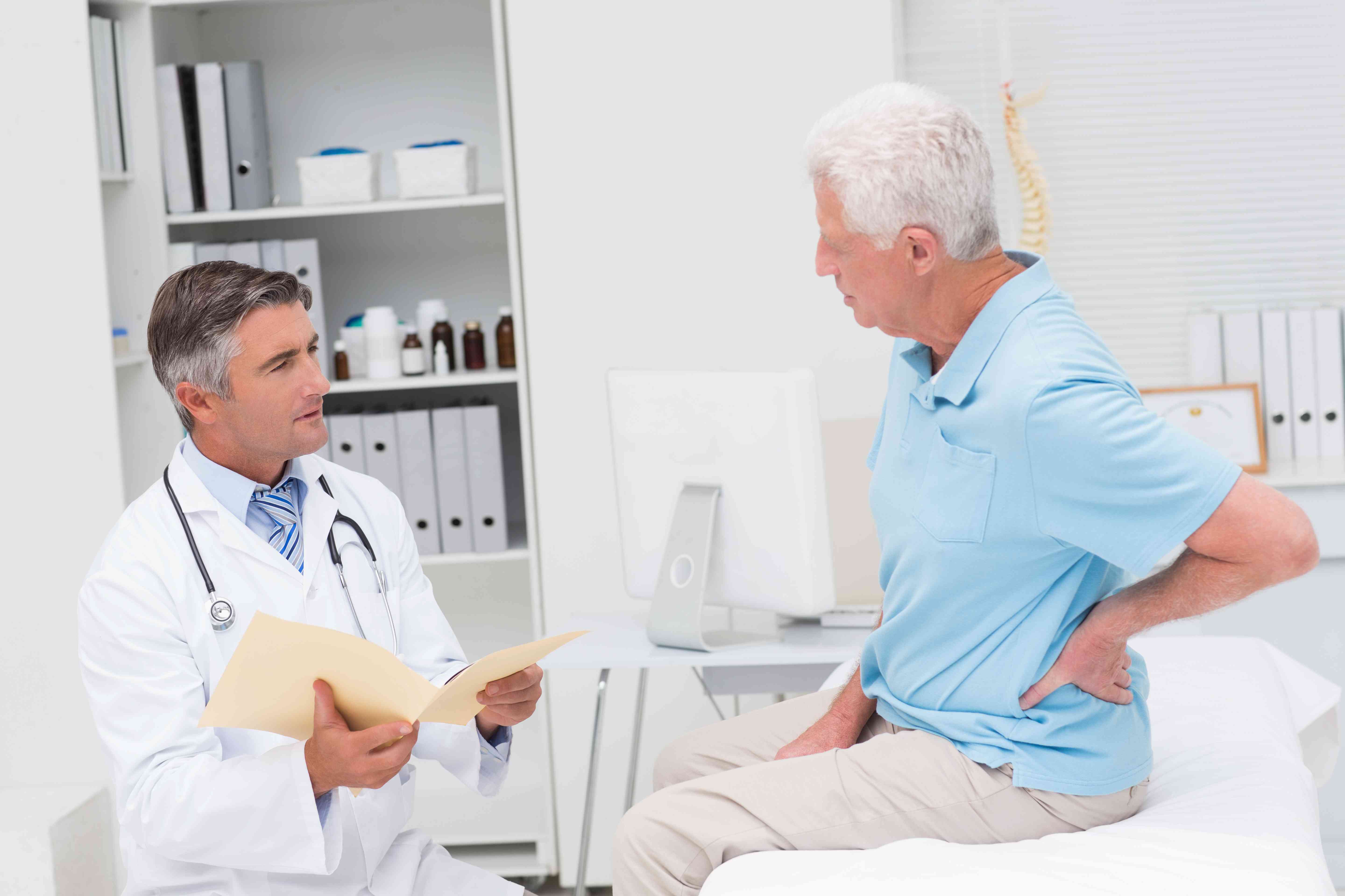 male-doctor-discussing-reports-with-senior-patient-suffering-from-backache-clinic-compressed